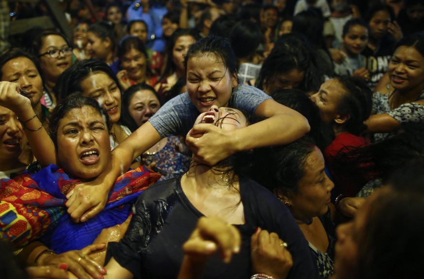epa05544813 Nepalese women and young girls struggle to drink homemade alcohol poured through a pipe sticking out of the mouth of Swet Bhairab, a god of Power, during the Indra Jatra festival at Basant ...