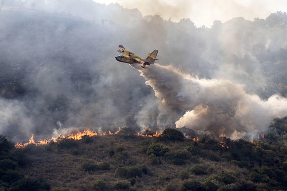 epa09411392 A firefighting plane douse the forest fire consuming the Catillo hill in Tivoli, near Rome, Italy, 12 August 2021. A civil defense helicopter, two Canadair firefighters and a carabinieri h ...