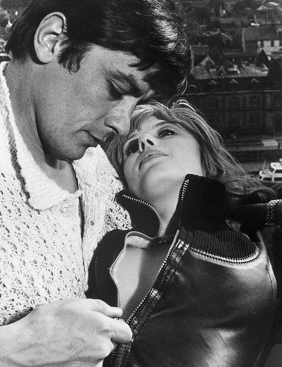 French actor Alain Delon zips Marianne Faithfull&#039;s leather jacket in a scene from their movie Girl on a Motorcycle.