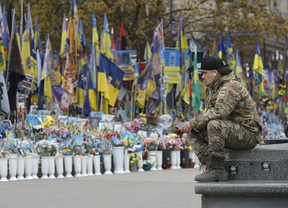 epa12902961 A man in military uniform sits near a makeshift memorial dedicated to the fallen Ukrainian soldiers and international volunteers in Independence Square in Kyiv, Ukraine, 20 April 2026, ami ...