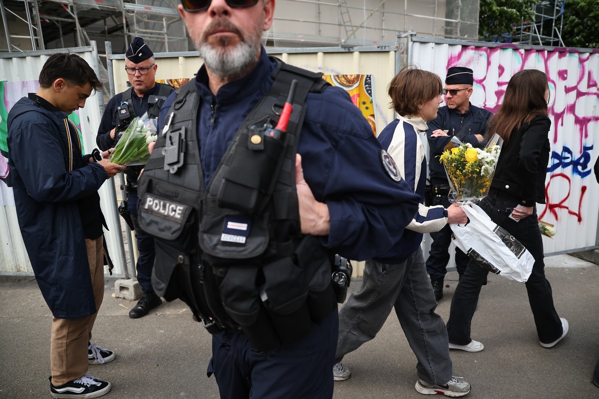 epa12054188 Police members guard students who arrive with flowers for a gathering at the Notre-Dame de Toutes-Aides high school, where a student stabbed several teenagers the day before, in Nantes, Fr ...