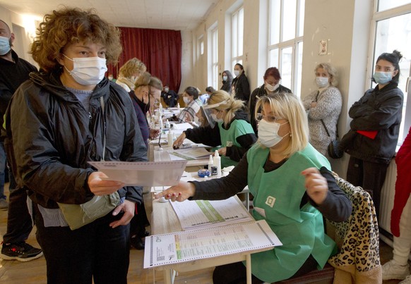 A woman is handed her ballot at a polling station during the national municipal elections in Tbilisi, Georgia, Saturday, Oct. 2, 2021. Georgians are voting in municipal elections across the country th ...