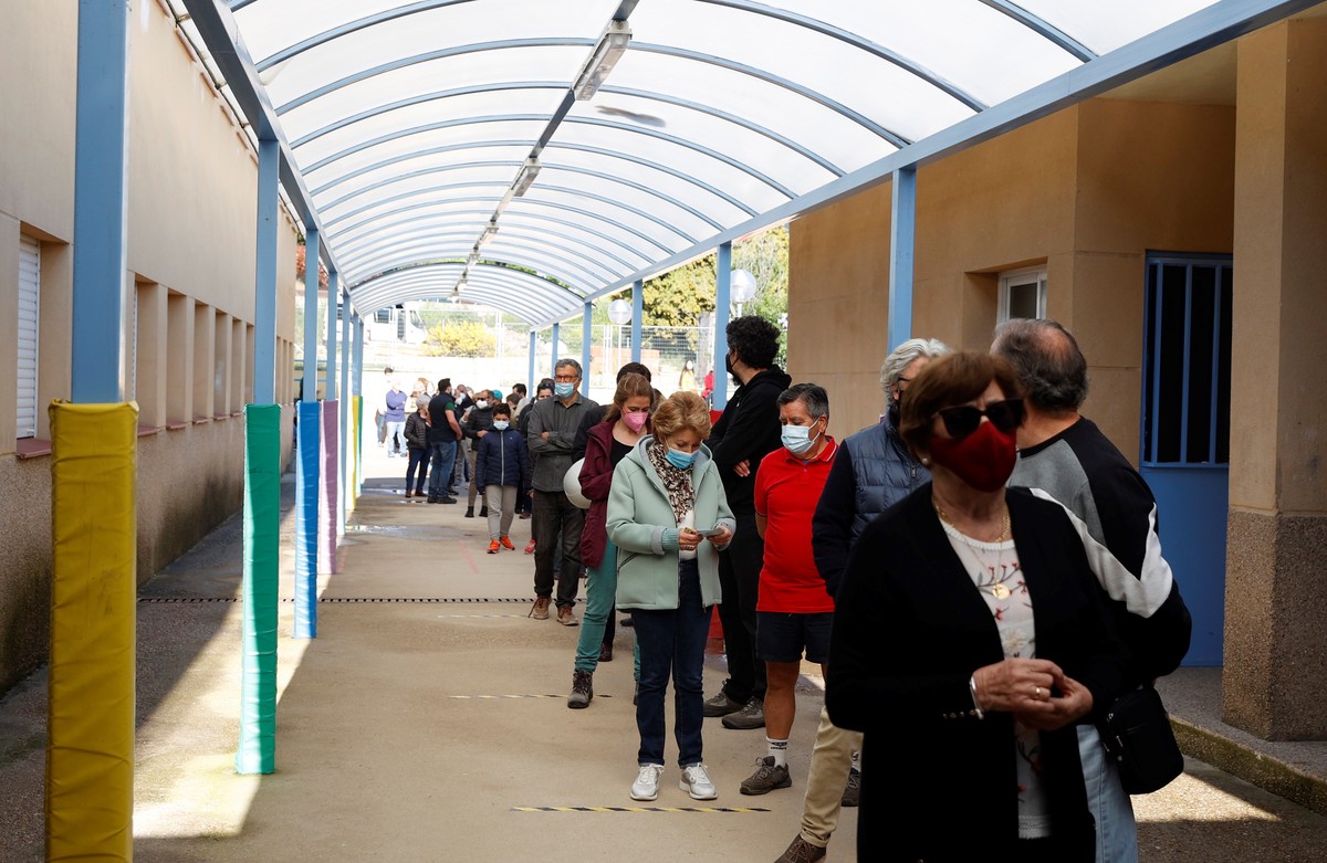 epa09176752 Voters wait in a long queue outside a polling station during Madrid's regional election, in the town of Galapagar, Madrid, Spain, 04 May 2021. Some 5.11 million citizens are called to ...