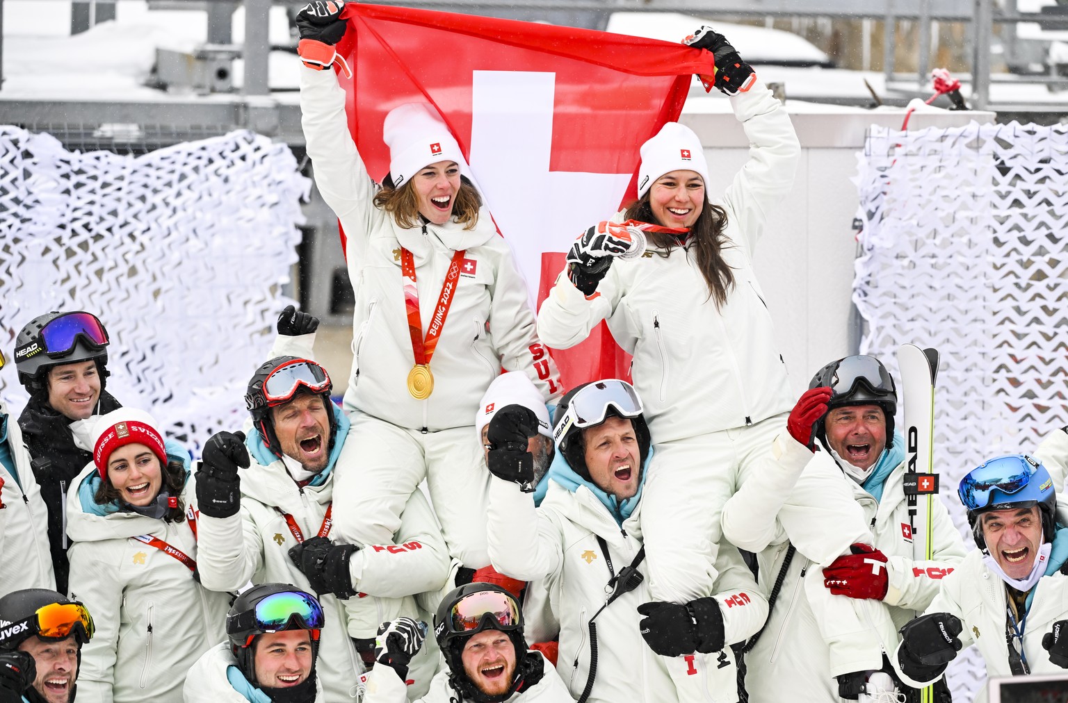 epa09765005 Gold medalist Michelle Gisin (up L) of Switzerland and silver medalist Wendy Holdener of Switzerland celebrate with their team after the victory ceremony of the Women&#039;s Alpine Skiing  ...