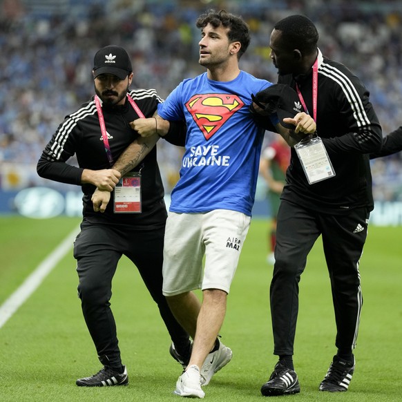 A protester is taken off the pitch during the World Cup group H soccer match between Portugal and Uruguay, at the Lusail Stadium in Lusail, Qatar, Monday, Nov. 28, 2022. (AP Photo/Aijaz Rahi)