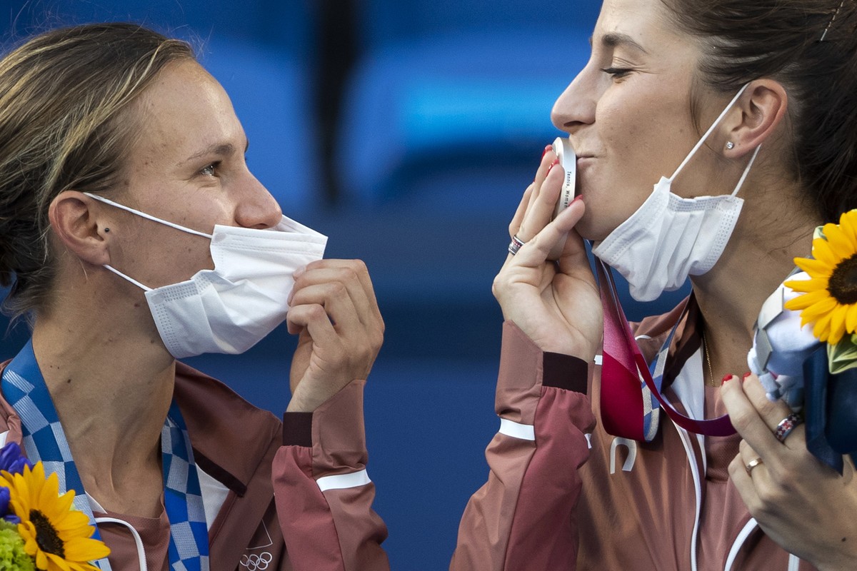 Switzerland's Belinda Bencic, right, kisses her silver medal next to teammate Viktorija Golubic on the podium after the women's tennis doubles gold medal match against Barbora Krejcikova and ...