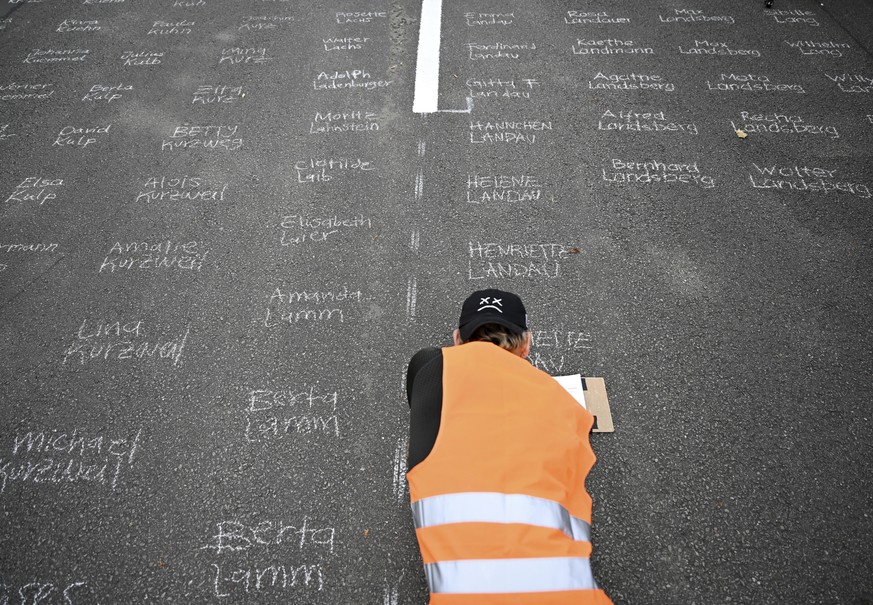 With white school chalk, Alejandro Streinesberger writes the names of Jews from Frankfurt, murdered during the Holocaust on the street during the art project &#039;Writing against forgetting&#039; at  ...