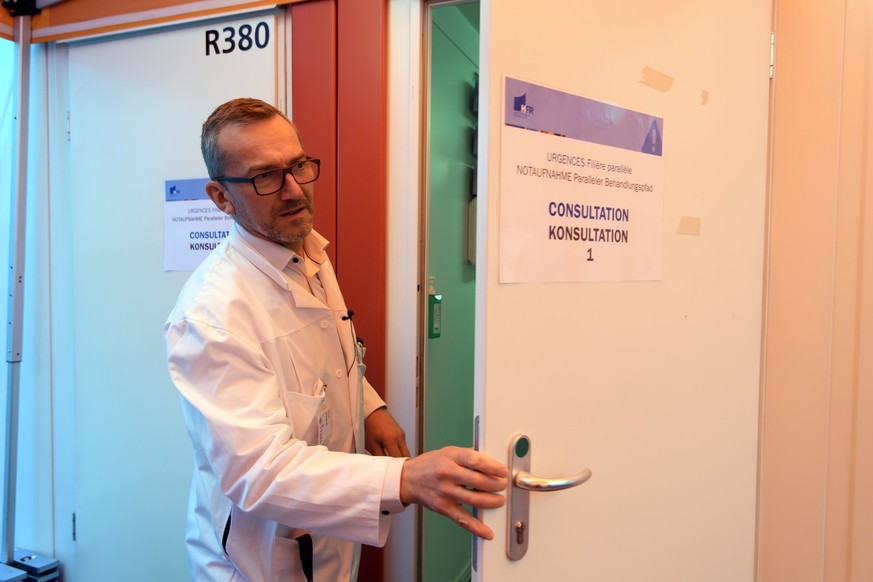 Doctor Vincent Ribordy, transversal Chief Physician of the HFR Emergency Department opens a door of a consultation container, under a COVID-19 consultation tent, front of the main entrance of the emer ...