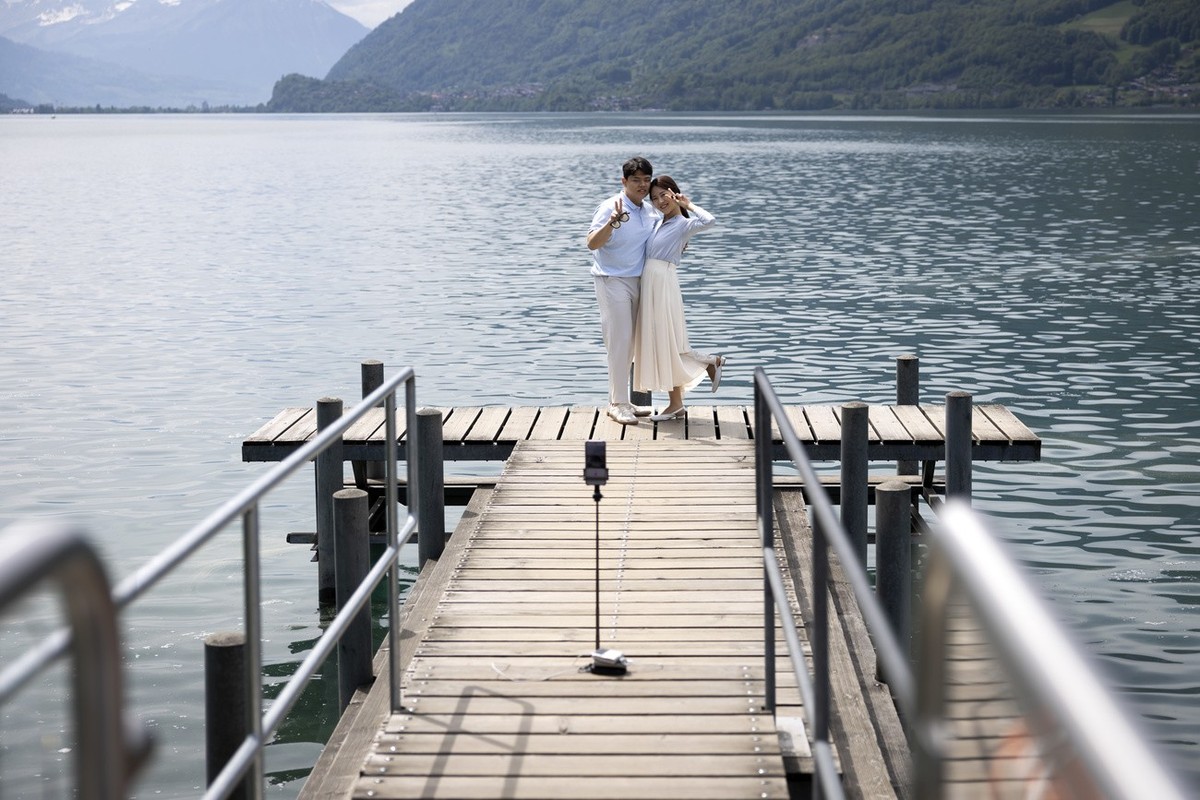 Korean visitors take selfie pictures at the pier in Iseltwald, Switzerland, Sunday, May 21, 2023. Lots of Asian TV fans and tourists visit the place because the romantic Korean Netflix drama 'Cra ...