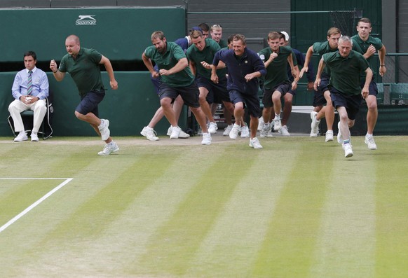 Ground staff run on to put the covers on before a rain delay during the Men&#039;s Singles Final match between Novak Djokovic of Serbia and Roger Federer of Switzerland at the Wimbledon Tennis Champio ...