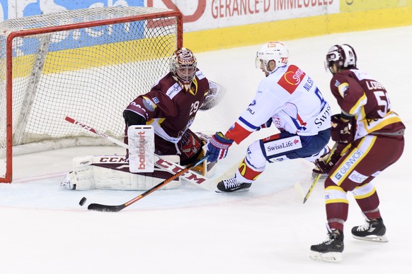 Le joueur zurichois, Robert Nilsson, centre, a la lutte pour le puck avec le joueur Genevois, Romain Loeffel, droite, devant le gardien genevois, Robert Mayer, gauche, lors du match du championnat sui ...