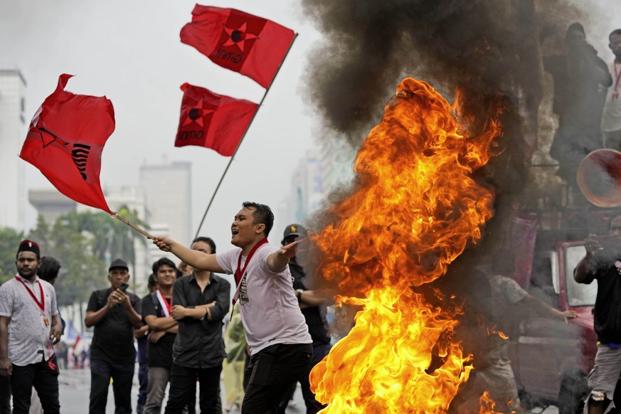 Student activists wave flags as they burn a tire during a rally against sharp increases in fuel prices, in Jakarta, Indonesia, Thursday, Sept. 8, 2022. The Indonesian government increased the fuel pri ...