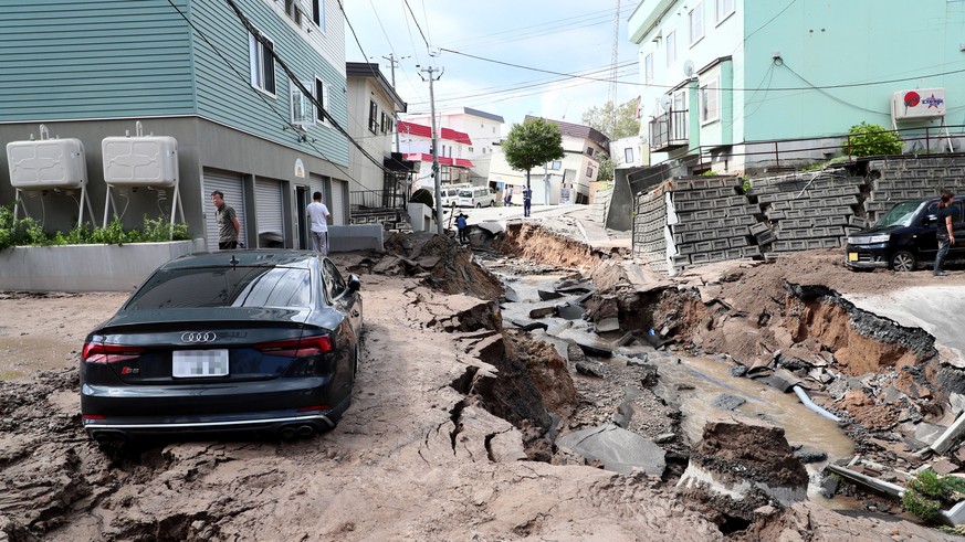 epa07000036 A mud covered car sits in the middle of a destroyed street following a powerful earthquake in Sapporo, Hokkaido, northern Japan, 06 September 2018. According to the Japan Meteorological Ag ...