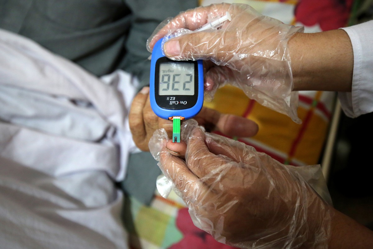 epa10974372 A health official takes the Glucometer random blood sugar test of a patient during a medical treatment in a ward at the Lady Reading government hospital, on the occasion of 'World Dia ...