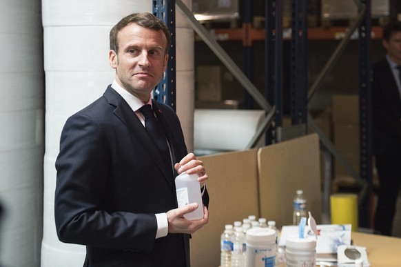 French President Emmanuel Macron holds a bottle of hydro alcoholic gel as he visits the Kolmi-Hopen protective face masks factory in Saint-Barthelemy-d'Anjou near Angers, central France, Tuesday March 31, 2020. French President Emmanuel Macron used a visit to a regional sanitary mask factory as a platform for an address to reassure the quarantine-hit nation that France was serious about urgently manufacturing masks. The new coronavirus causes mild or moderate symptoms for most people, but for some, especially older adults and people with existing health problems, it can cause more severe illness or death. (Loic Venance, Pool via AP)