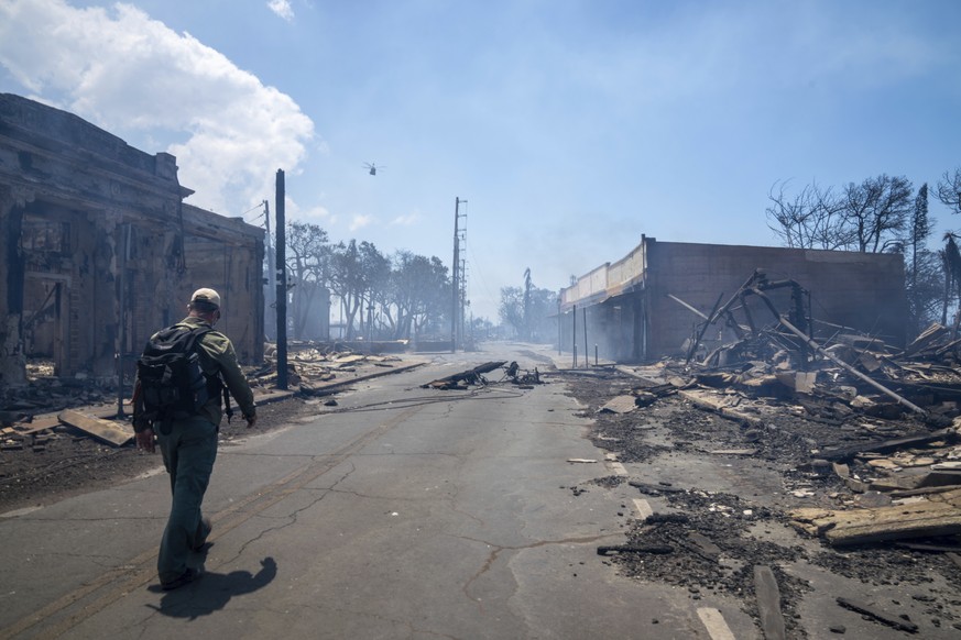 A man walks past wildfire wreckage on Wednesday, Aug. 9, 2023, in Lahaina, Hawaii. The scene at one of Maui's tourist hubs on Thursday looked like a wasteland, with homes and entire blocks reduce ...