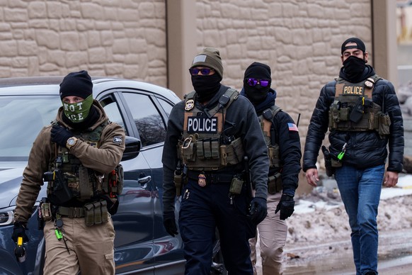 Immigration and Customs Enforcement (ICE) agents, including one wearing a 'NOT ICE' face covering, walk near their vehicles, Thursday, Jan. 15, 2026, in Richfield, Minn. (AP Photo/Adam Gray) ...