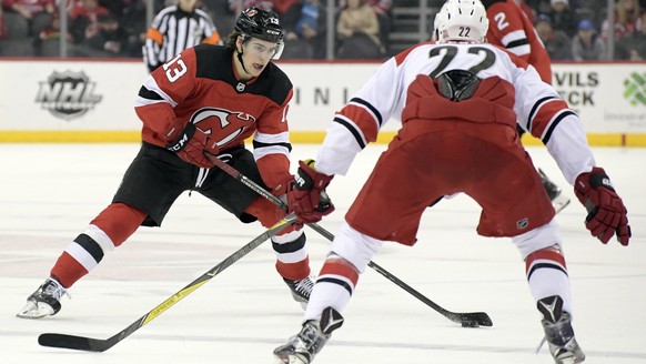 New Jersey Devils center Nico Hischier (13) looks to pass the puck as Carolina Hurricanes defenseman Brett Pesce (22) defends during the second period of an NHL hockey game Thursday, Feb. 15, 2018, in ...