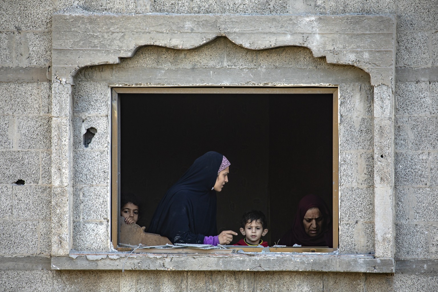 epa11169234 Palestinians stand at their window after an Israeli airstrike on the Rafah refugee camp, southern Gaza Strip, 21 February 2024. More than 29,100 Palestinians and over 1,300 Israelis have b ...
