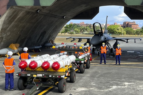 Military personnel stand next to Harpoon A-84, anti-ship missiles and AIM-120 and AIM-9 air-to-air missiles prepared for a weapon loading drills in front of a F16V fighter jet at the Hualien Airbase i ...