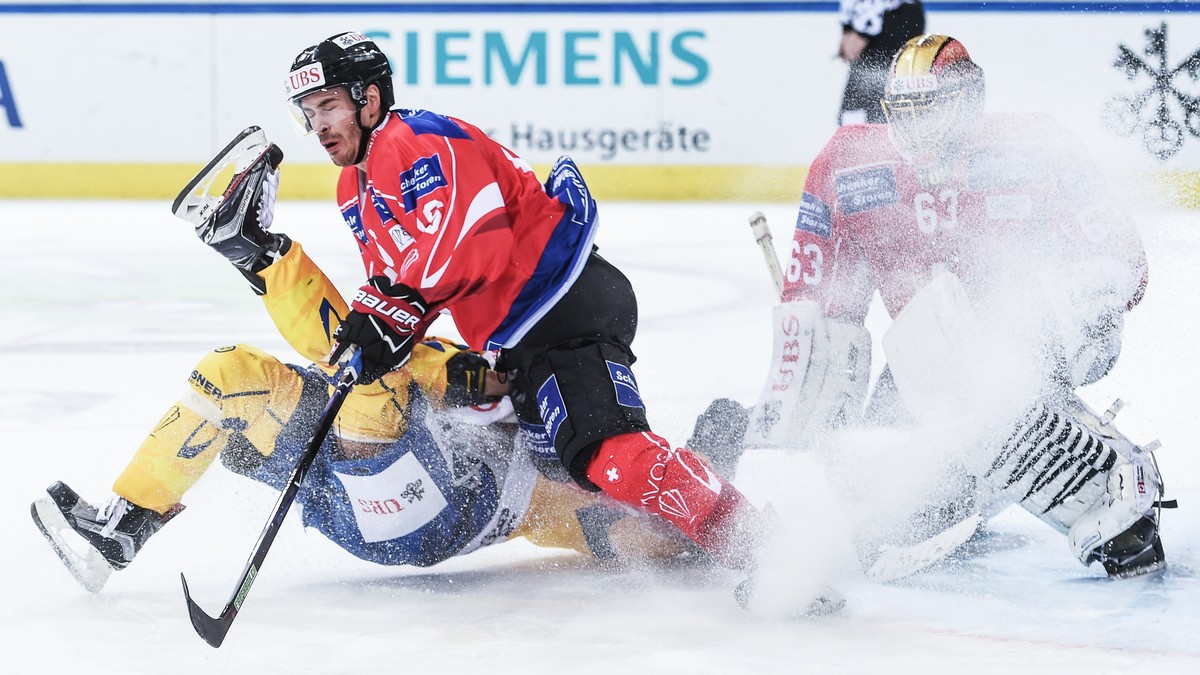 Davos`Andres Ambuehl fights for the puck with Suisse player Raphael Diaz and goalkeeper Leonardo Genoni during the game between Team Suisse and HC Davos at the 91th Spengler Cup ice hockey tournament ...