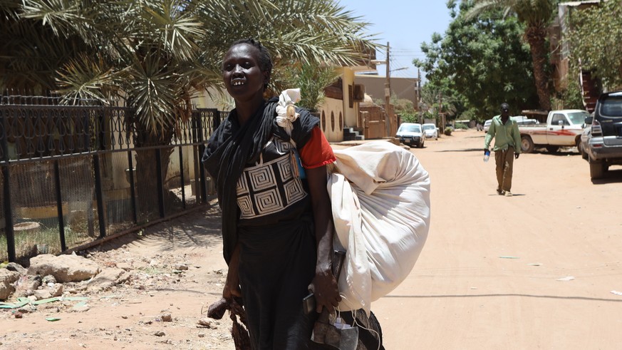 epa10579958 A Sudanese woman carries her belongings on a street in Khartoum, Sudan, 19 April 2023. A power struggle erupted since 15 April between the Sudanese army led by army Chief General Abdel Fat ...