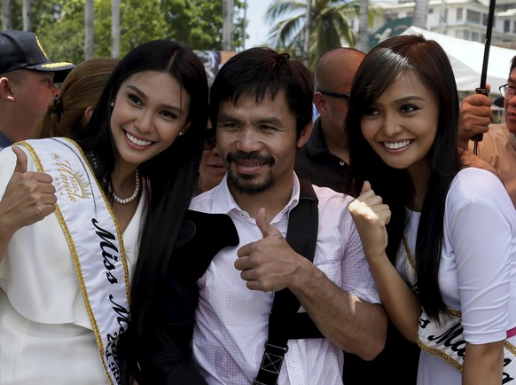 epa04745644 Filipino boxing icon Manny &#039;Pacman&#039; Pacquiao (C), wearing an arm-sling, poses for a photograph during a welcoming parade in Manila, Philippines, 13 May 2015. Philippine boxer Man ...