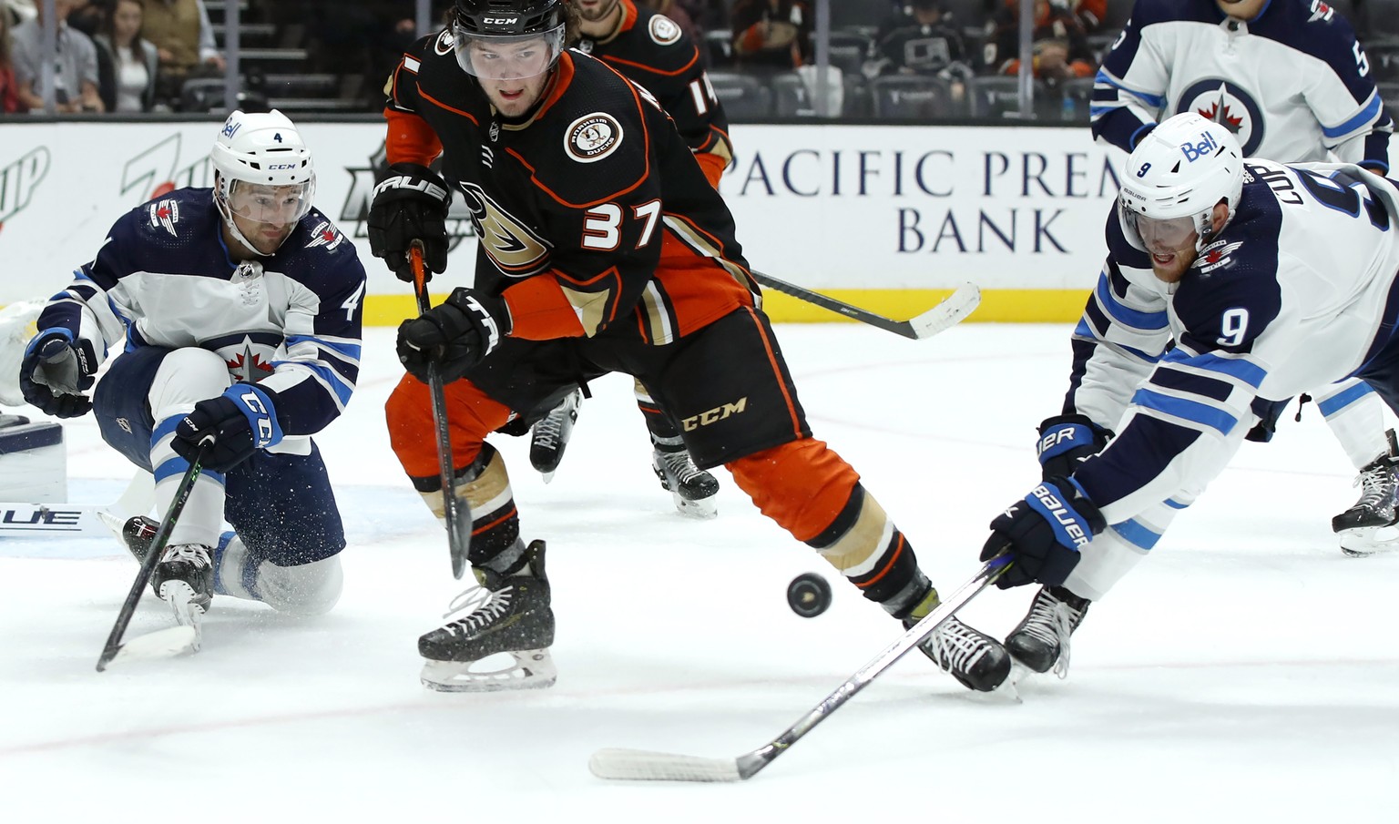 Anaheim Ducks center Mason McTavish (37) and Winnipeg Jets center Andrew Copp (9) work for the puck with defenseman Neal Pionk (4) watching during the second period of an NHL hockey game in Anaheim, C ...