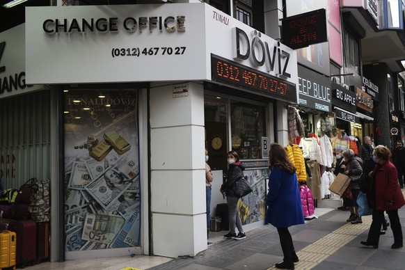 People stand outside a currency exchange shop, in Ankara, Turkey, Tuesday, Nov. 23, 2021. The Turkish currency weakened by nearly 10% against the U.S. dollar Tuesday, a day after President Recep Tayyi ...