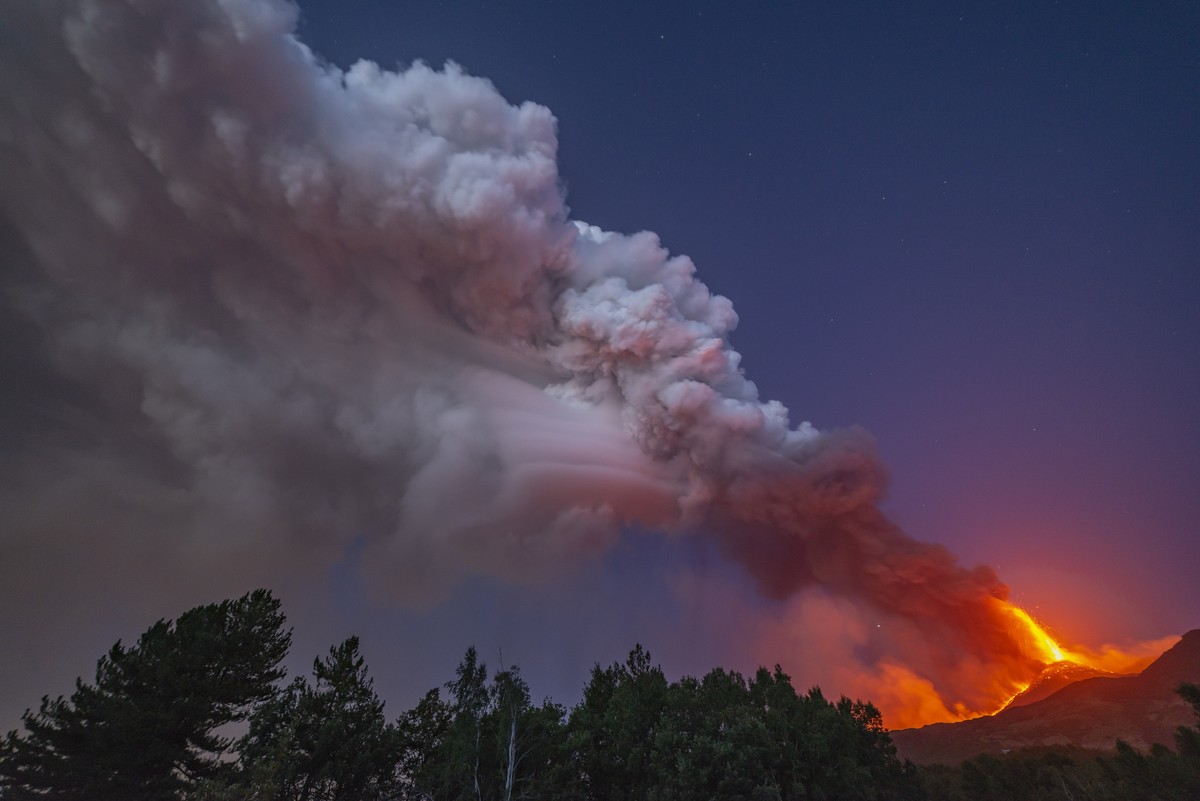 Smoke billows from the Mt Etna volcano as seen from Linguaglossa, Sicily, Monday, Aug. 9, 2021. Europe's most active volcano remains active scattering ashes around a vastly populated area on its  ...