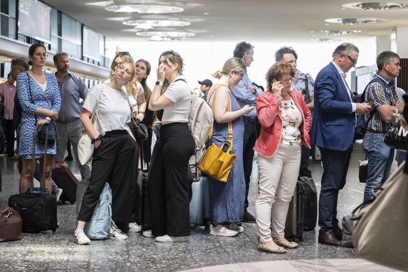 Fluggaeste warten vor einer Anzeigetafel am Mittwoch, 15. Juni 2022, auf dem Flughafen in Zuerich. Wegen einer Informatikpanne von Skyguide sind die Flughaefen Zuerich und Genf derzeit lahmgelegt. Es  ...