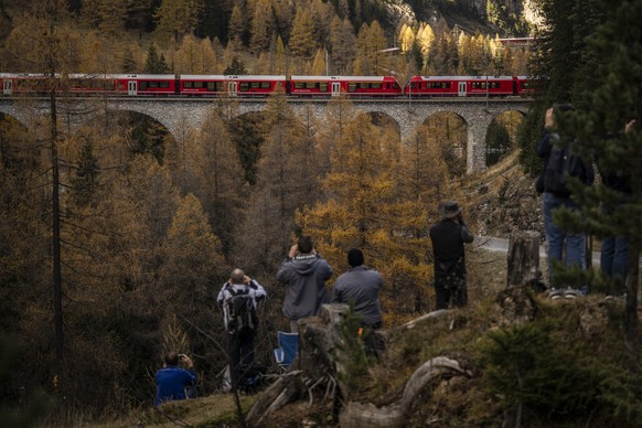 epa10273063 Spectators watch a train of the Rhaetian Railway (RHB) on its way to set a world record for longest passenger train, in Preda, Switzerland, 29 October 2022. The 1.91-kilometer-long train i ...