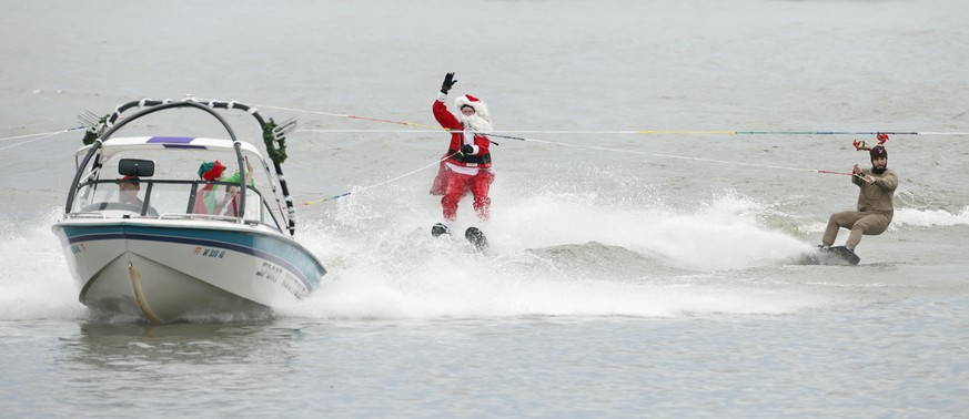 A man dressed as Santa Claus waves to the crowd as he water skis next to a man dressed as reindeer, on the Potomac River in Alexandria, Virginia, on Christmas Eve December 24, 2015. REUTERS/Kevin Lama ...