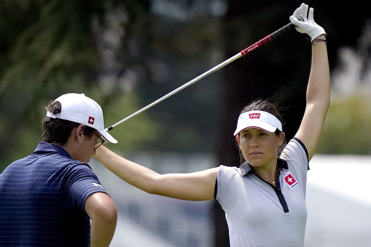 Albane Valenzuela, of Switzerland, stretches on the 11th fairway as her brother and caddy, Alexis Valenzuela, stands with her bag during a practice round prior to the women's golf event at the 20 ...