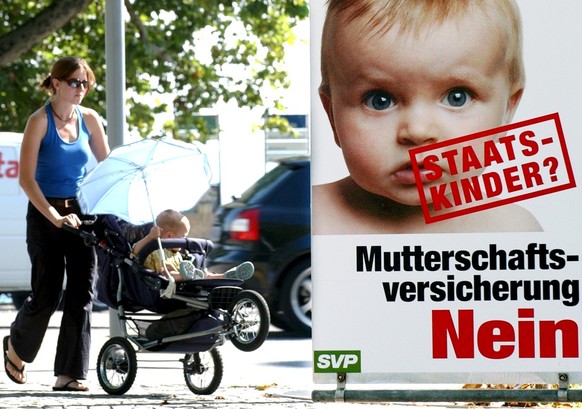 Eine Frau geht am Donnerstag, 9. September 2004, in Zuerich mit ihrem Kinderwagen an einem von der SVP lancierten Plakat vorbei, welches sich gegen eine Mutterschaftsversicherung ausspricht. Die Volks ...