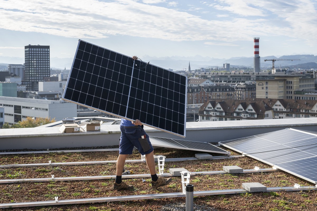 Der Monteur einer Elektroinstallationsfirma montiert eine Solaranlage auf dem Dach eines Wohnhaus in Zuerich, fotografiert am Freitag, 29. September 2023. (KEYSTONE/Christian Beutler)..