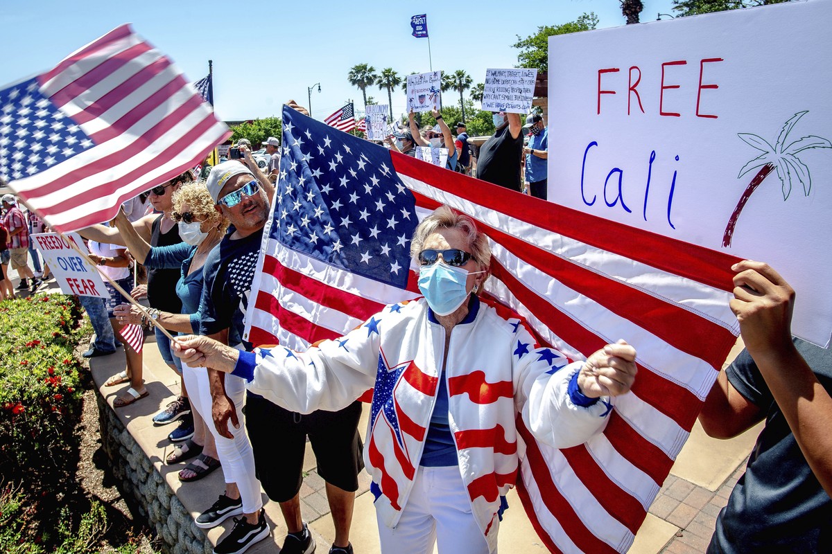 Jan Clever, 81, center, of Rancho Cucamonga, center, waves a U.S. flag while wearing a protective mask during a demonstration against California's stay-at-home orders that were put in place due t ...
