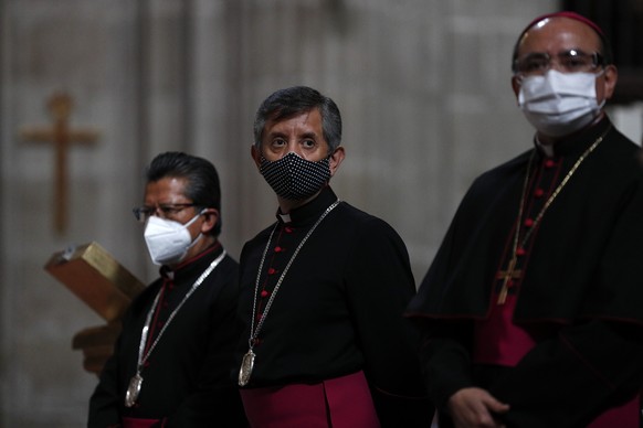 Catholic priests stand inside the Metropolitan Cathedral ahead of the first Mass open to the public amidst the ongoing coronavirus pandemic, in Mexico City, Sunday, July 26, 2020. (AP Photo/Rebecca Blackwell)
