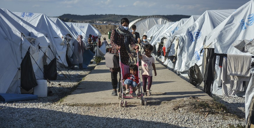 Migrants walk after a rainstorm at the Kara Tepe refugee camp, on the northeastern Aegean island of Lesbos, Greece, Wednesday, Oct. 14, 2020. Around 7,600 refugees and migrants have settled at the new ...