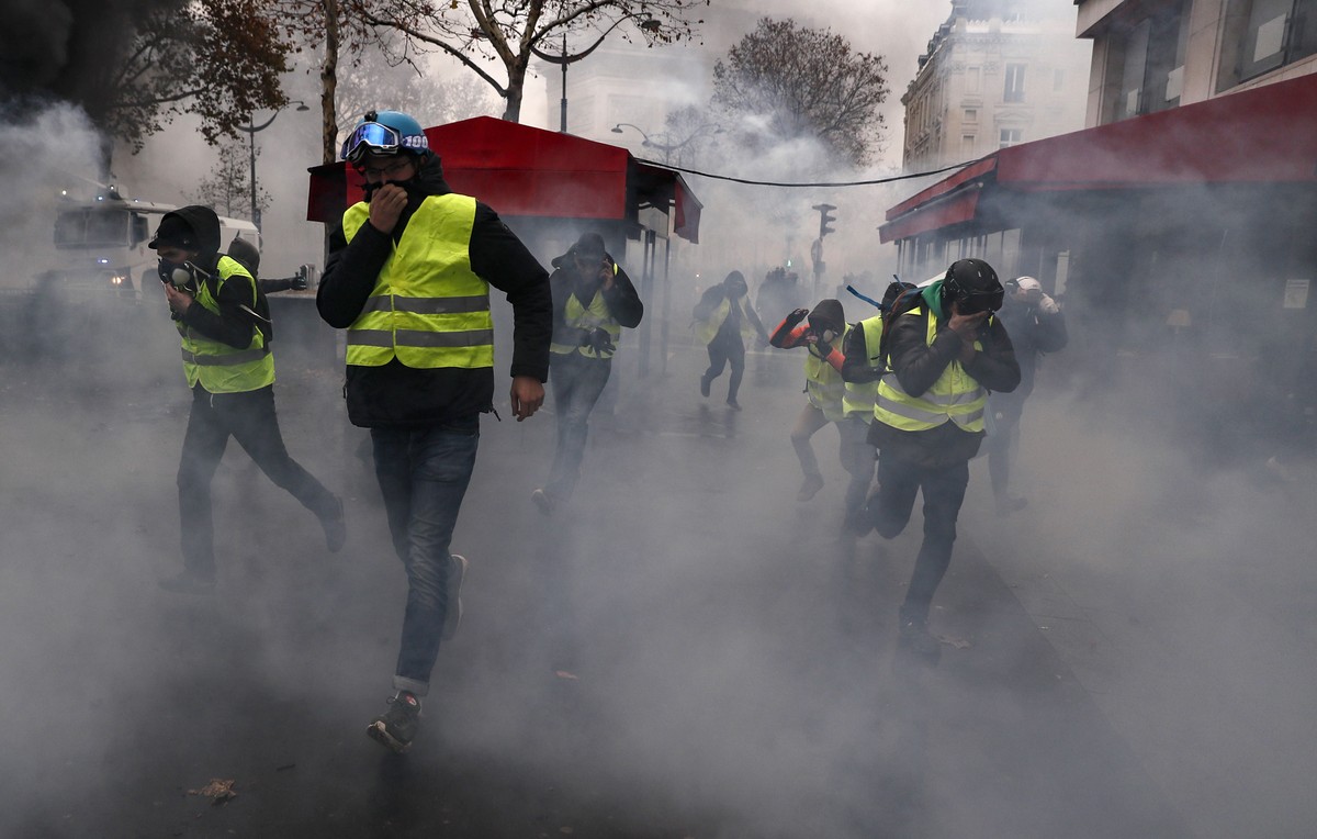 epa07201223 Protesters wearing yellow vests (gilets jaunes) run from tear gas during a demonstration over high fuel prices on the Champs Elysee in Paris, France, 01 December 2018. The so-called ' ...
