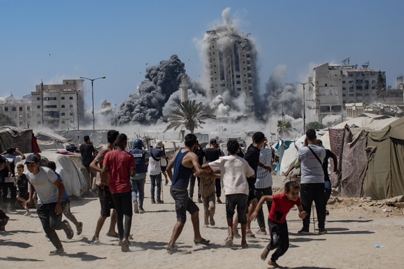 epa12354558 Palestinians react as smoke rises from the Mushtaha Tower following an Israeli airstrike in the west of Gaza City, Gaza Strip, 05 September 2025. More than 64,000 Palestinians have been ki ...