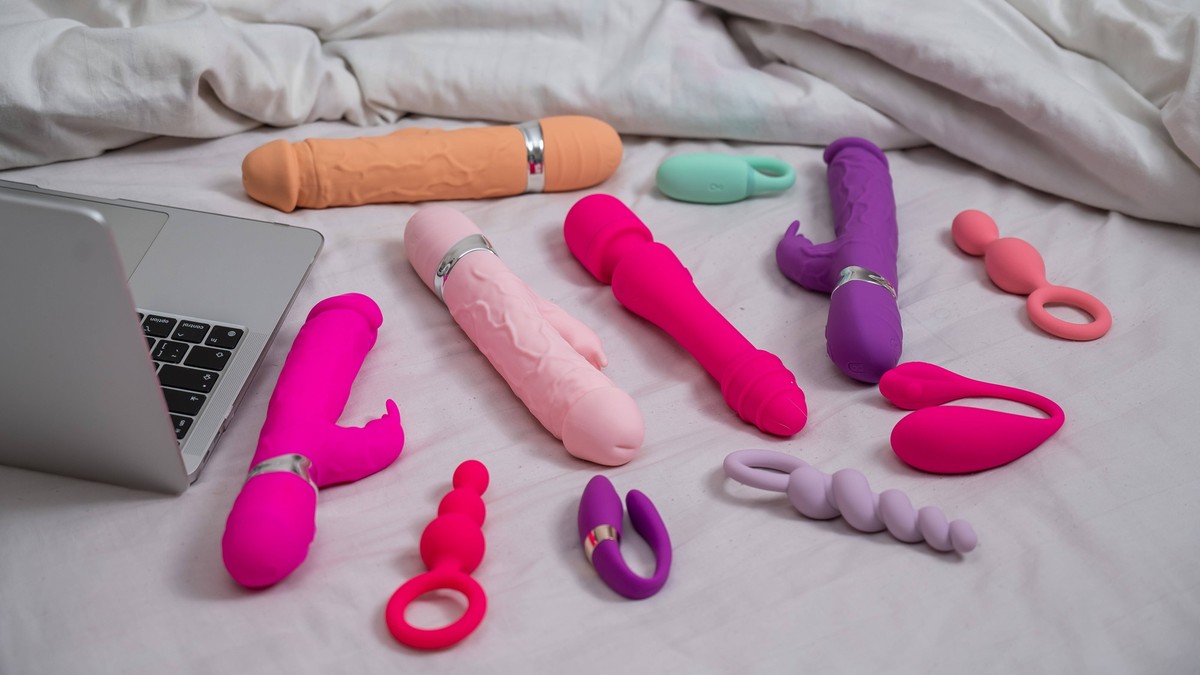Collection of sex toys on a white sheet. Various vibrators and a laptop on the bed. Collection of sex toys on a white sheet. Various vibrators and a laptop on the bed, 97770798.jpg RECORD DATE NOT STA ...