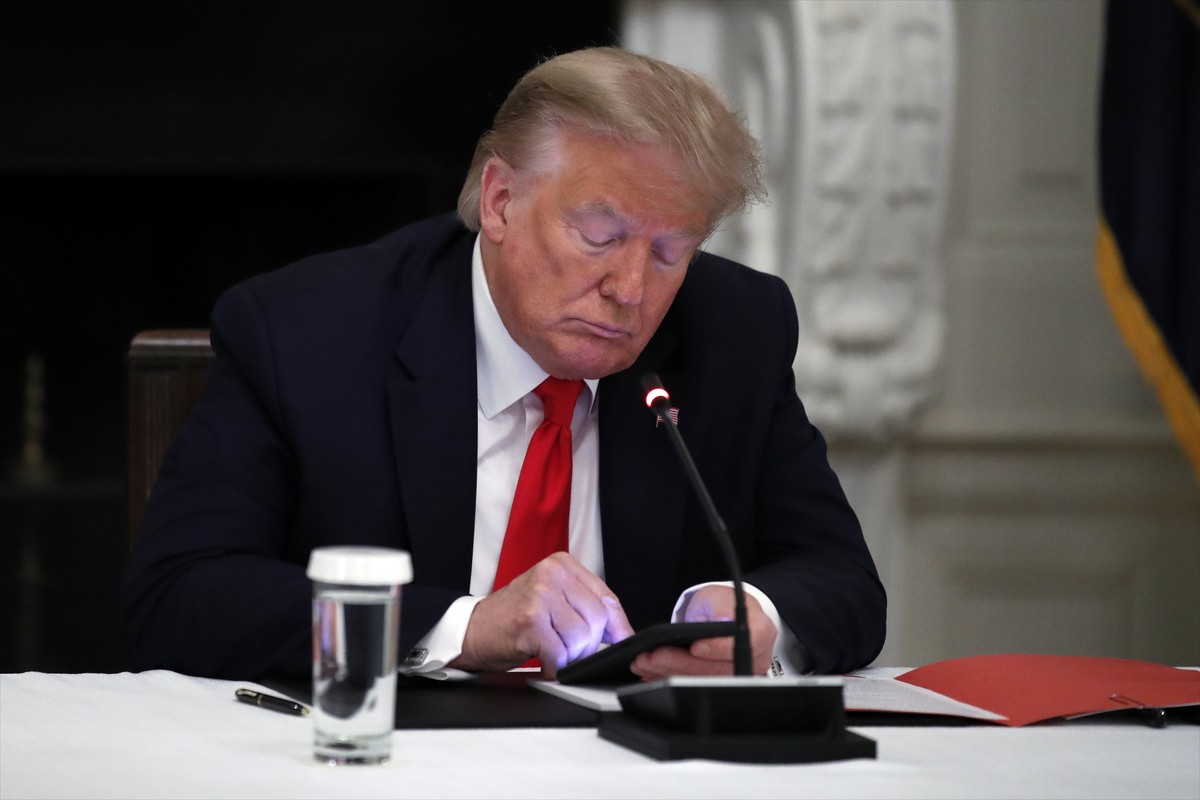 FILE - In this Thursday, June 18, 2020 file photo, President Donald Trump looks at his phone during a roundtable with governors on the reopening of America's small businesses, in the State Dining ...