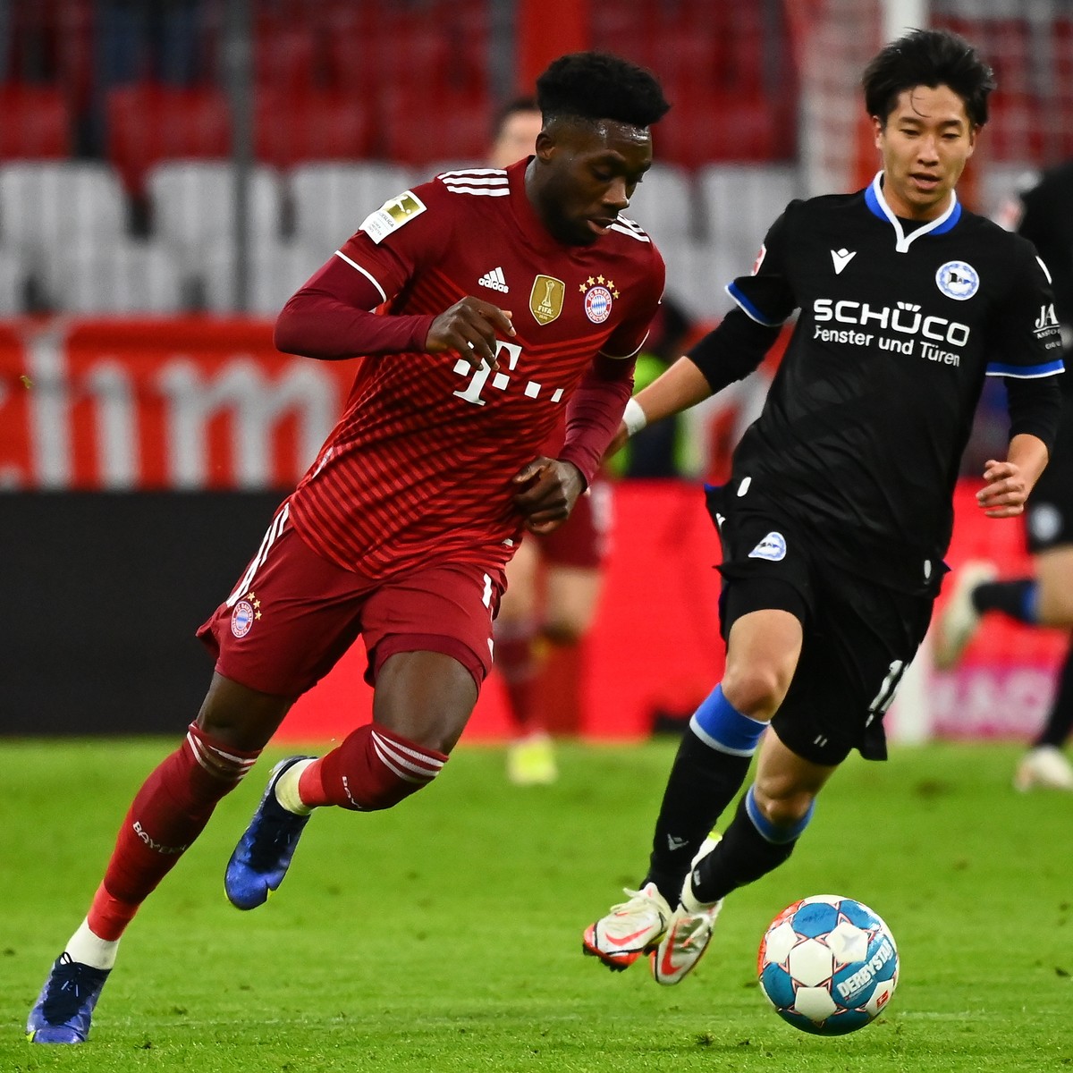 epa09607709 Munich's Alphonso Davies (L) in action against Bielefeld's Masaya Okugawa (R) during the German Bundesliga soccer match between Bayern Muenchen and Arminia Bielefeld in Munich, G ...