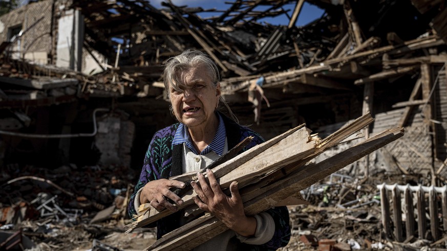A woman collects wood for heating from a destroyed school where Russian forces were based in the recently retaken area of Izium, Ukraine, Monday, Sept. 19, 2022. Residents of Izium, a city recaptured  ...