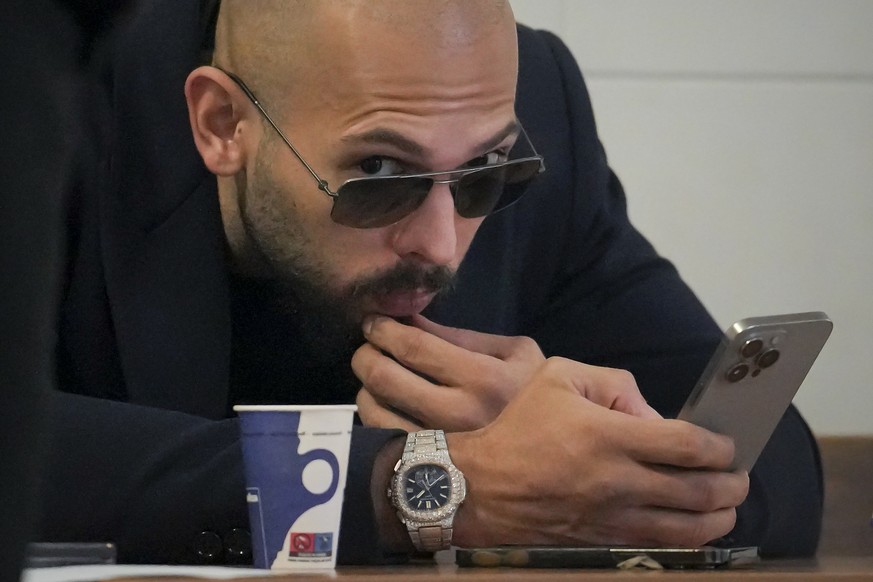 Andrew Tate checks his mobile phone inside the Court of Appeal building in Bucharest, Romania, Friday, Dec. 22, 2023. (AP Photo/Vadim Ghirda)