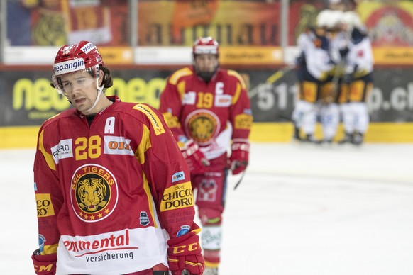 Langnaus Yannick-Lennart Albrecht, links, und Pascal Berger, Mitte, geschlagen, die Zuger Spieler jubeln, rechts, waehrend dem Meisterschaftsspiel der National League zwischen den SCL Tigers und dem E ...