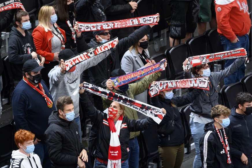 Des supporters lausannois portant un masque de protection facial regardent le match du championnat suisse de hockey sur glace de National League entre le Lausanne HC et le SCL Langnau Tigers ce jeudi  ...