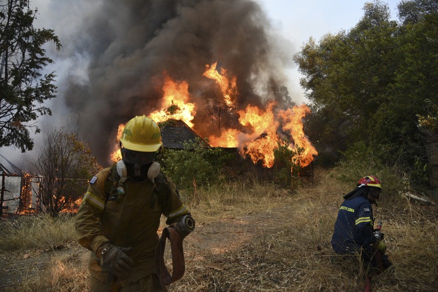 Firefighters operate during a wildfire near Lampiri village, west of Patras, Greece, Saturday, Jul. 31, 2021. The fire, which started high up on a mountain slope, has moved dangerously close to seasid ...