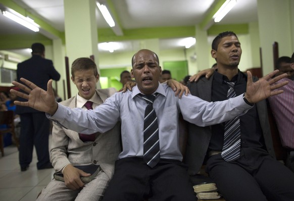 In this Sept. 28, 2014 photo, members of the God&#039;s Assembly, Restoration Ministry Church react to the words of Pentecostal preacher Dione dos Santos in the Coreia shantytown, in Rio de Janeiro, B ...